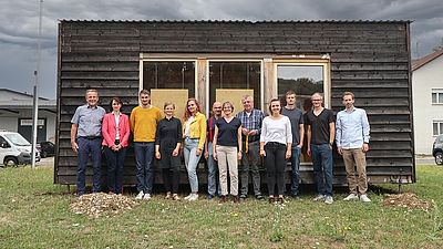 Gruppe eines Forschungsprojekts vor einem Holzhaus