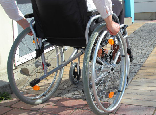 Rollstuhlfahrerin fährt auf Rollstuhlrampe
