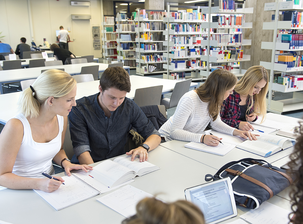 Studierende sitzen in der Bibliothek an Tischen und lernen 