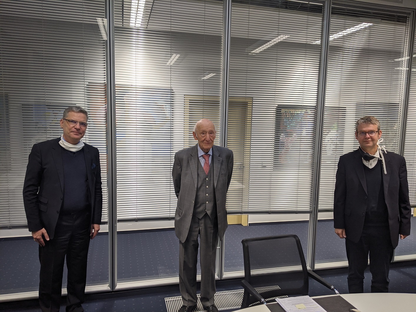 Drei Männer stehen in einem Konferenzraum