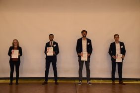 Gruppenfoto mit vier Personen, die eine Urkunde in der Hand halten