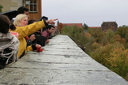 Internationale Studierende schauen von Stadtmauer herunter