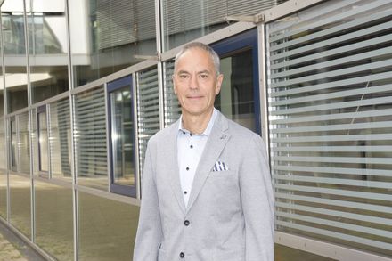 Mann in Anzugjacke steht auf dem Campus