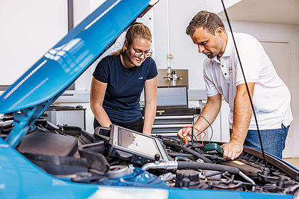 two persons at a car looking into it