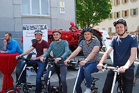 Vier Studenten auf leichten, klappbaren Fahrrädern stellen Forschungsprojekt vor