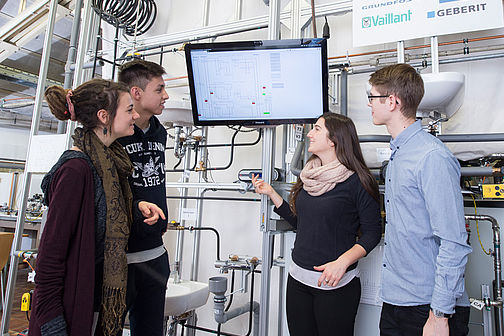 Two young women and two young men look at a screen.