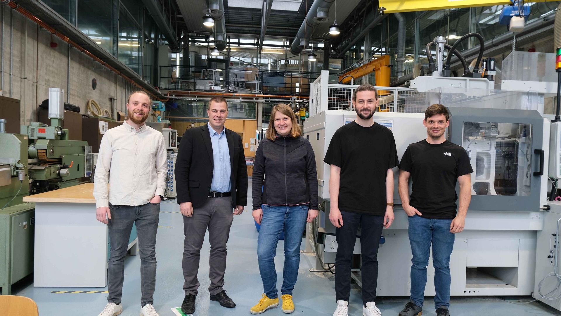 Das Team des Labors für Kunststofftechnik. Fünf Personen stehen vor den Maschinen im Labor.
