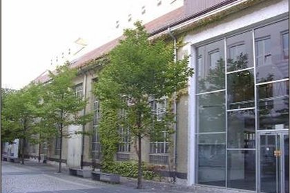 Ein Gebäude mit Glaswand und Bäumen davor.