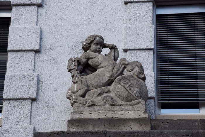 Ein Zentaur h&auml;lt einen Blitz in der rechten Hand und blickt auf den Eingang herunter..