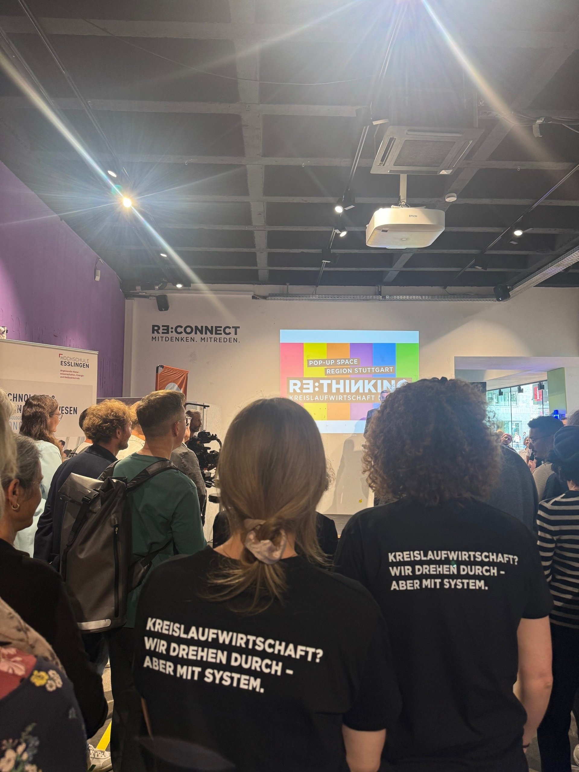 Zwei Frauen mit T-Shirts mit der Aufschrift "Kreislaufwirtschaft? Wir drehen durch - aber mit System"