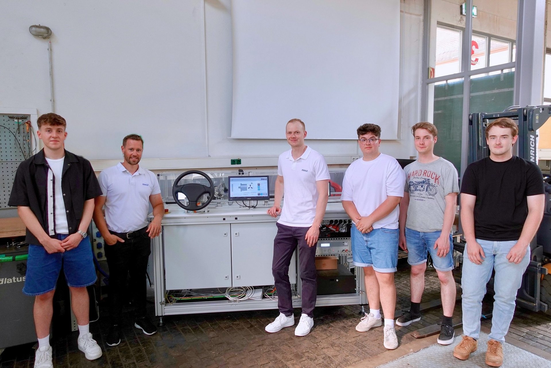 Studierende und zwei Mitarbeiter von Mahle mit einem Lenkungsprüfstand