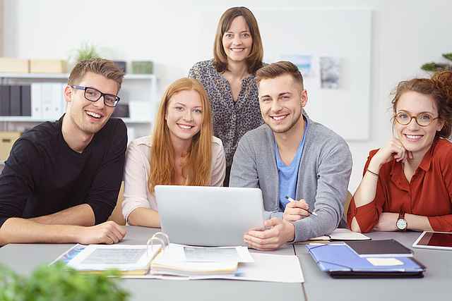 Gruppe von jungen Frauen und Männern um einen Computer