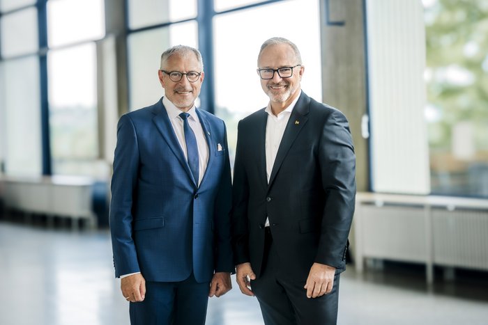 Zwei Männer im Anzug stehen nah beieinander