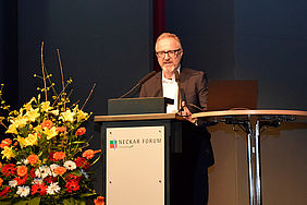 Markus Sontheimer am Rednerpult mit Blumenschmuck daneben