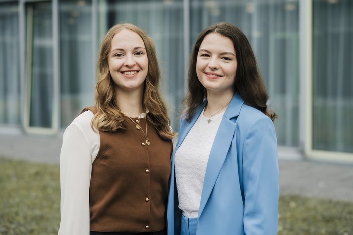 Zwei Graduierte blicken in die Kamera