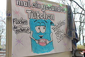 Auf einem Whiteboard ist ein Comic gemalt. Die Überschrift lautet "Mal ein gesundes Tütchen". Eine blaue Müslitüte, welche selbst Müsli aus einer Schale isst. Die Müslitüte sagt "Flocken die rocken"