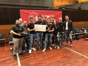 Gruppe von Studierenden hält Scheck in die Höhe