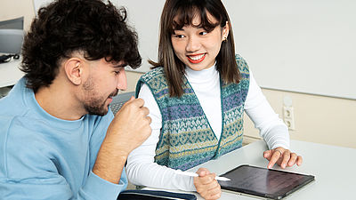 Zwei Studierende sitzen am Tablet