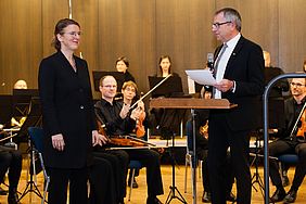 Ein Mann und eine Frau stehen vor einem Orchester