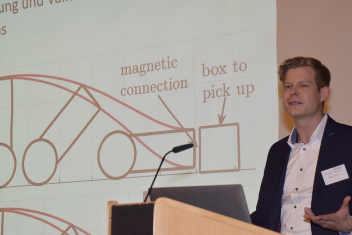 Mann an Rednerpult mit Pr&auml;sentation