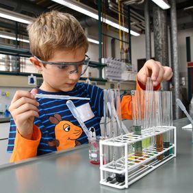 Kleiner Junge steht im Chemielabor der Hochschule Esslingen
