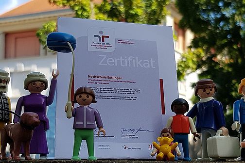 Playmobil family in front of certificate and university building