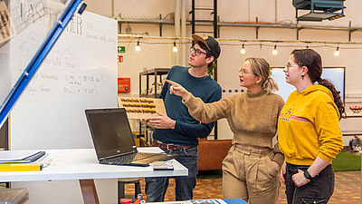 Zwei Frauen und ein Mann stehen im MakerSpacES! und unterhalten sich über den Lasercutter.