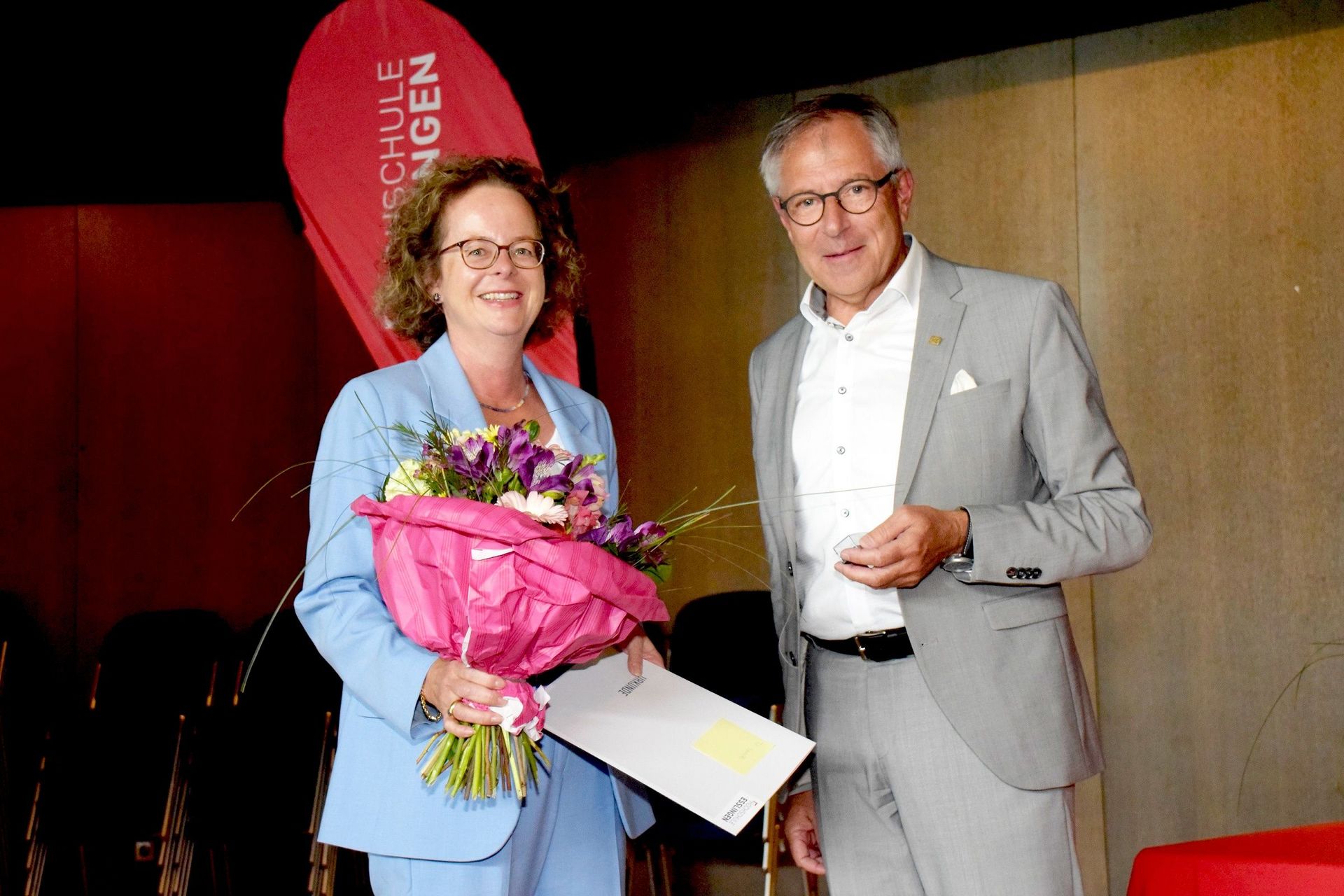 Frau mit Blumenstrauß und Mann schauen in die Kamera