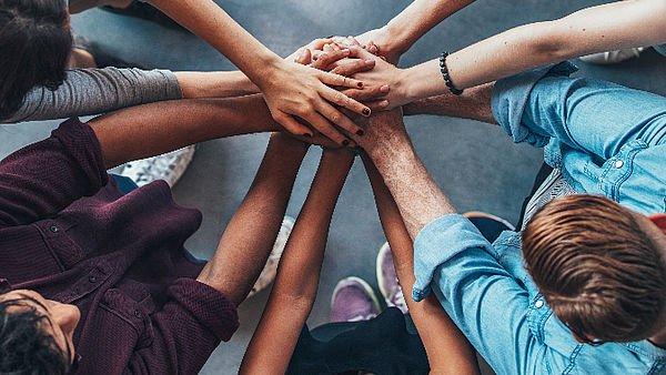 In a circle, hands are placed on top of each other in the middle