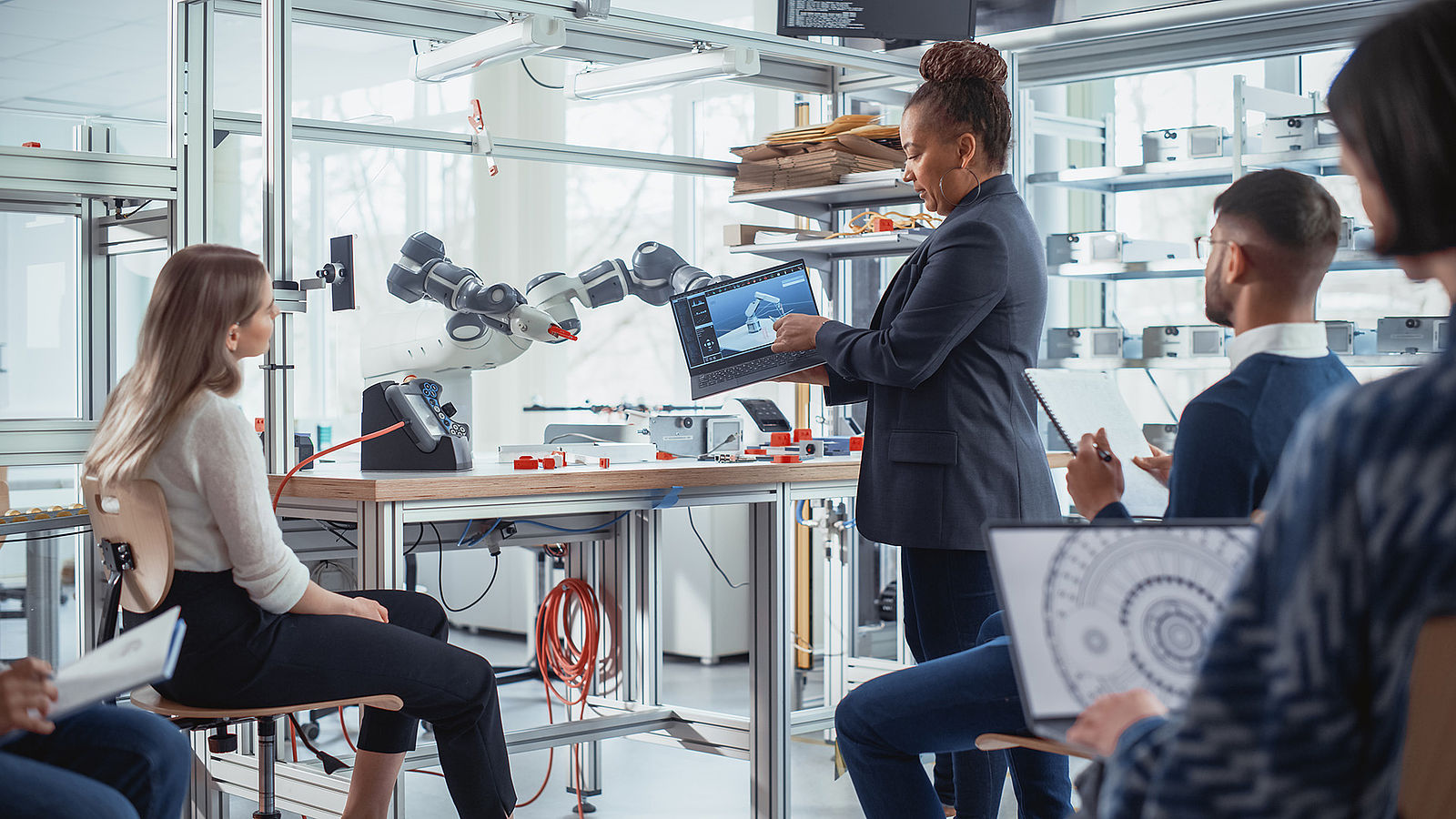 A group of information scientists discuss the programming of a robot arm.