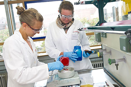 Zwei Studentinnen in Laborkleidung führen einen Versuch durch