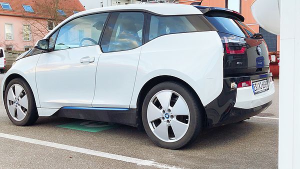 Ein schwarz-weißes Elektro-Auto vor einer Ladesäule.