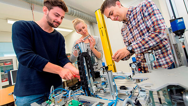 3 Studierenden arbeiten an einer Maschine