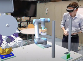 Ein junger Mann rechts im Bild trägt eine Virtual Reality Brille. Links davon sind reale und virtuelle Maschinenbauteile.