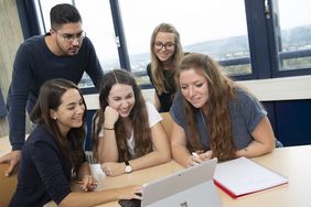 Gruppe von Studierenden schaut in ein Tablet