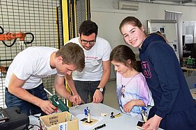 Zwei Kinder basteln mit Studenten zusammen 