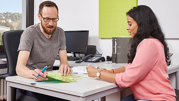 Ein und eine Frau sitzen am Tisch im Beratungsgespräch