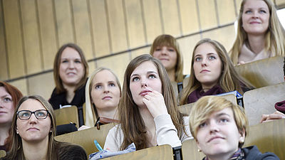 mehrere Studierende im Hörsaal von vorne beim Zuhören einer Vorlesung