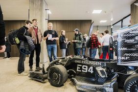 Erstsemester schauen sich den Rennstall mit Rennautos an