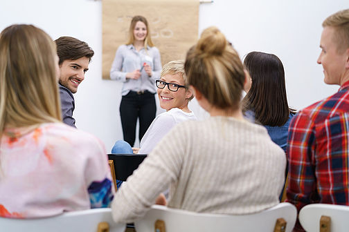 Woman stands before listeners and speaks