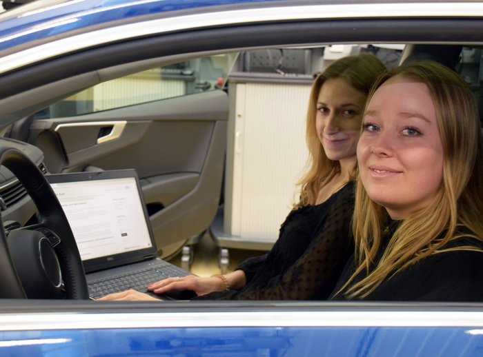 Zwei junge Frauen sitzen vorne in einem Auto.
