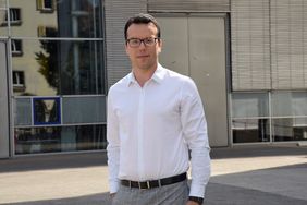 Mann steht auf dem Campus der Hochschule