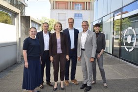 Sechs Männer und Frauen stehen auf dem Campus der Hochschule