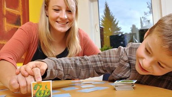 Eine Betreuerin spielt mit einem kleinen Jungen Memorie