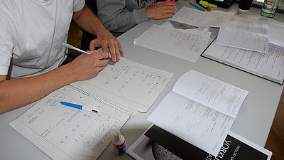 Students in math class calculate tasks and practice. The documents are on the table.å
