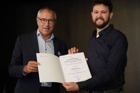 Zwei Männer mit einer Urkunde in der Hand