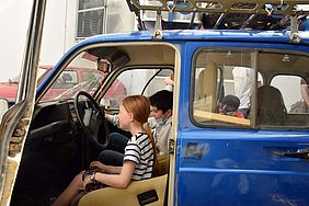 Eine Schülerin sitzt auf dem Fahrersitz des Rallyeautos.