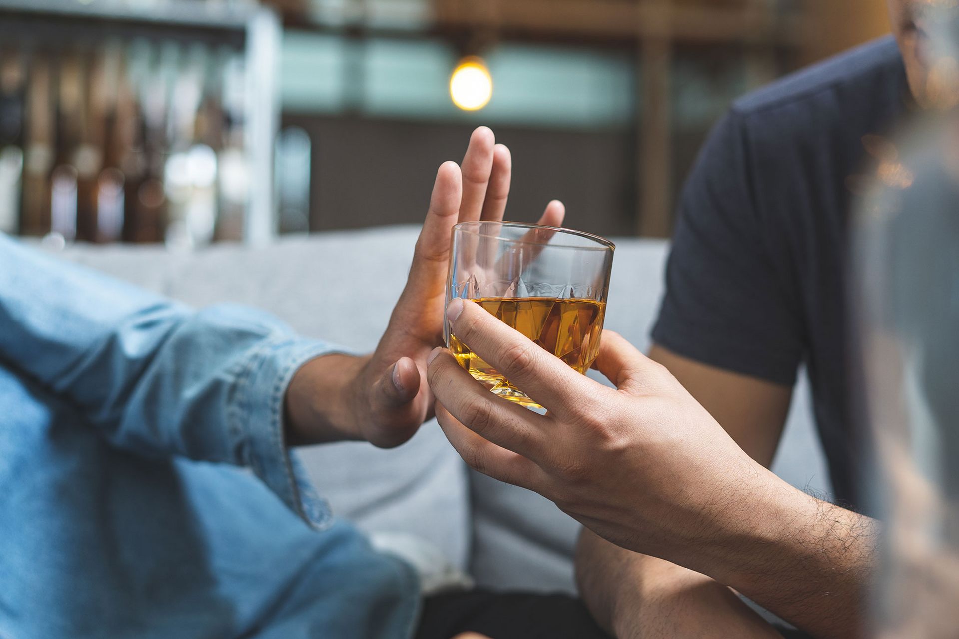 Eine Person lehnt ein angebotenes Glas ab.