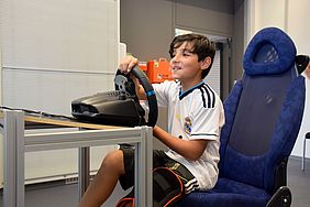 Ein Schüler sitzt im Fahrsimulator und hält das Lenkrad mit beiden Händen.
