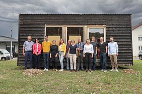 Gruppe eines Forschungsprojekts vor einem Holzhaus